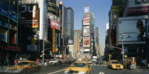Times Square.  Daytime view with traffic and advertising hoardings  speeding yellow cabs in the foreground.