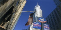 Chrysler Building.  Seen from below  between other buildings with American Stars and Stripes flag and road sign in the foreground.