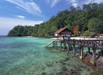 Pulau Paya marine national park with landing jetty over coral reef and tree lined beach behind
