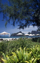 Pantai Rhu beach from the gardens of the Radisson Resort hotel with umbrellas on the beachAsian Beaches Malaysian Sand Sandy Seaside Shore Southeast Asia Tourism Holidaymakers Scenic Southern Sunbath...
