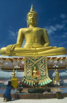 Woman praying before statue of Buddha at the Big Buddha Temple on the north coast