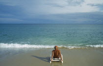 Lamai beach with lone male tourist sitting on a sunbed on the empty beach