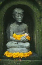 Small Hindu shrine detail of seated figure with flower offerings in the Miro Garden restaurant