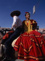 Couple in Flamenco costume riding horseback at the April Fair in Los Remedios district