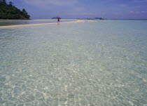 Lobagao Bay on the north coast of the island with a man in red walking along a sand bar