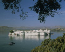 The Lake Palace in the middle of the lake with a covered boat making its way across the water