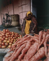 Female vegetable seller with red root vegetables and tomatoes