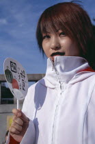 Harajuku District. Portrait of a teenage girl wearing a white jacket holding a fan