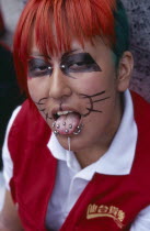 Harajuku District. Portrait of a teenage girl wearing cat whisker makeup with several tongue and facial piercings