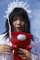 Harajuku District. Portrait of a teenage girl wearing white lace dress holding a red teddy bear