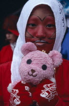 Harajuku District. Portrait of young teenage girl wearing red face paint and holding a pink teddy bear