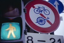 Green light of a pedestrian crossing next to bicycle road signs