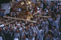 Shinjuku. Crowd of people carrying Mikoshi throught the street during a festival celebration