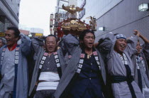Shinjuku. Men carrying Mikoshi throught the street during a festival celebration