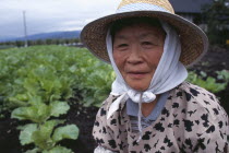 Woman wearing a hat beside vegetable plot