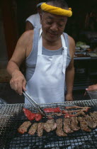 Tsukiji Fish Market. Man cooking red meat on an open grill