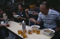 Tsukiji Fish Market. People eating with chopsticks at noodle stall