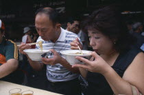Tsukiji Fish Market. People eating with chopsticks at noodle stall