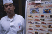 Tsukiji Fish Market with chef standing beside seafood menu board