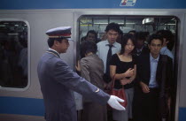 Passengers on crowded train at Ueno Station with train guard standing on the platform