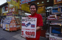 Akihabara Electronics District. Vendor holding poster outside his electrical store