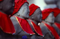 View along row of Jizo statues dressed in red bibs by bereaved mothers and other sufferers