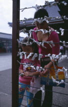 Asakusa. Woman and girl tying Omikuji or Fortune papers at Senso Ji Temple