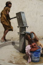 Children filling bucket and drinking from Tara water pump