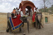Japanese tourists taking elephant ride with mounting platform behind them