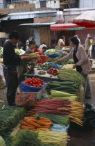 Covered food market with displays of fresh vegetables.