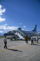 Domestic aircraft on runway with passengers disembarking.