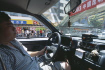 Interior of a taxi with view from passenger seat towards the driver.