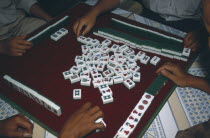 China, Yunnan, Mah Jong game being played with view over peoples hands on a tiled table. .