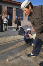 China, Gansu, Linxia. Donxiang ethnic minority Muslim boy playing with a spinning top.