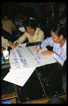 China, Yunnan Province, Simao. Pu er. Teachers sat around a table preparing a presentation on flip chat paper at a training workshop for teachers.