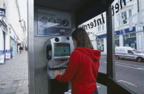 Communications, Phone Box, Young woman using a public BT Internet phone booth.