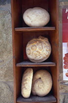 Traditional breads displayed on wooden shelves.