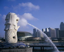 Merlion statue spouting water in to the Singapore River with the city skyline beyond