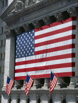 Wall Street stock exchange with stars and stripes flag draped across the colonnaded facade