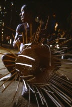 Macuna man weaving thin wooden strips to make basket.