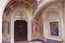 Interior with religious mosaics and paintings surrounding doorway and arch.