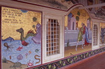 Detail of brightly coloured mosaics and paintings covering exterior wall of covered walkway.