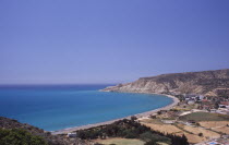 Mediterranean bay encircled by narrow strip of beach  agricultural land and distant headland.