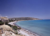 Quiet half moon beach and Pissouri Bay with surrounding rocky coastline  hotel and other buildings.