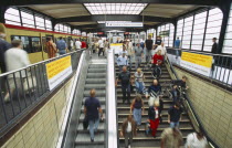 Interior of the Zoologischer Garten Railway station with people on stairs to platform and waiting train.