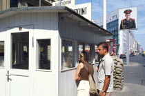 Check Point Charlie with tourists looking through the hut window