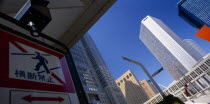 West Shinjuku District. Angled view looking toward the multi storey Tokyo Metropolitan Government Offices seen from tunnel with pedestrian crossing sign in the foreground