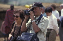 An American tourist films in a cultural manyatta set up to interface the Maasai directly with tourists.