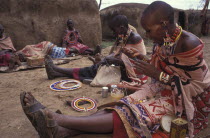 Maasai women making traditional crafts in a cultural  manyatta set up for tourists on the edge of the Maasai Mara game park.