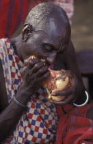 A maasai elder bites into a large beef bone during an initiation ceremony  which brings the Maasai Moran or young warriors into manhood. The Maasai diet consists almost entirely of meat blood and milk...
